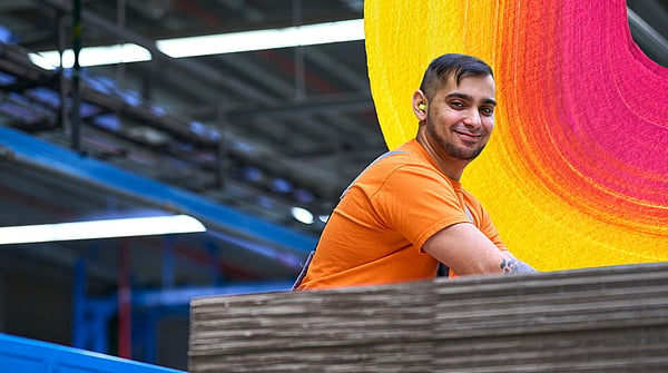 man in orange t-shirt at work in a factory setting